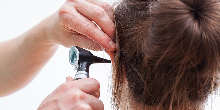 Ear examining with an otoscope, isolated background