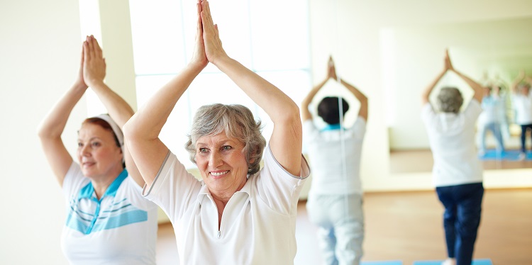 Portrait of two aged females doing yoga exercise in sport gym